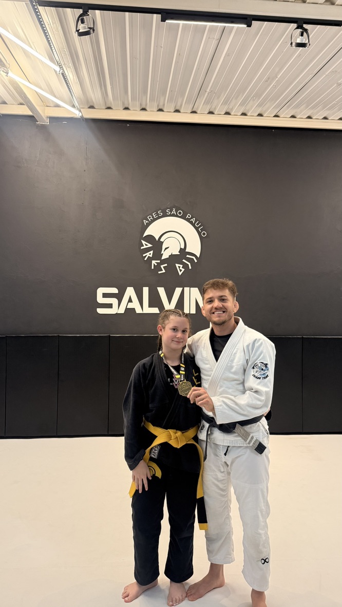 Aluna da Salvino BJJ com medalha ao lado do professor