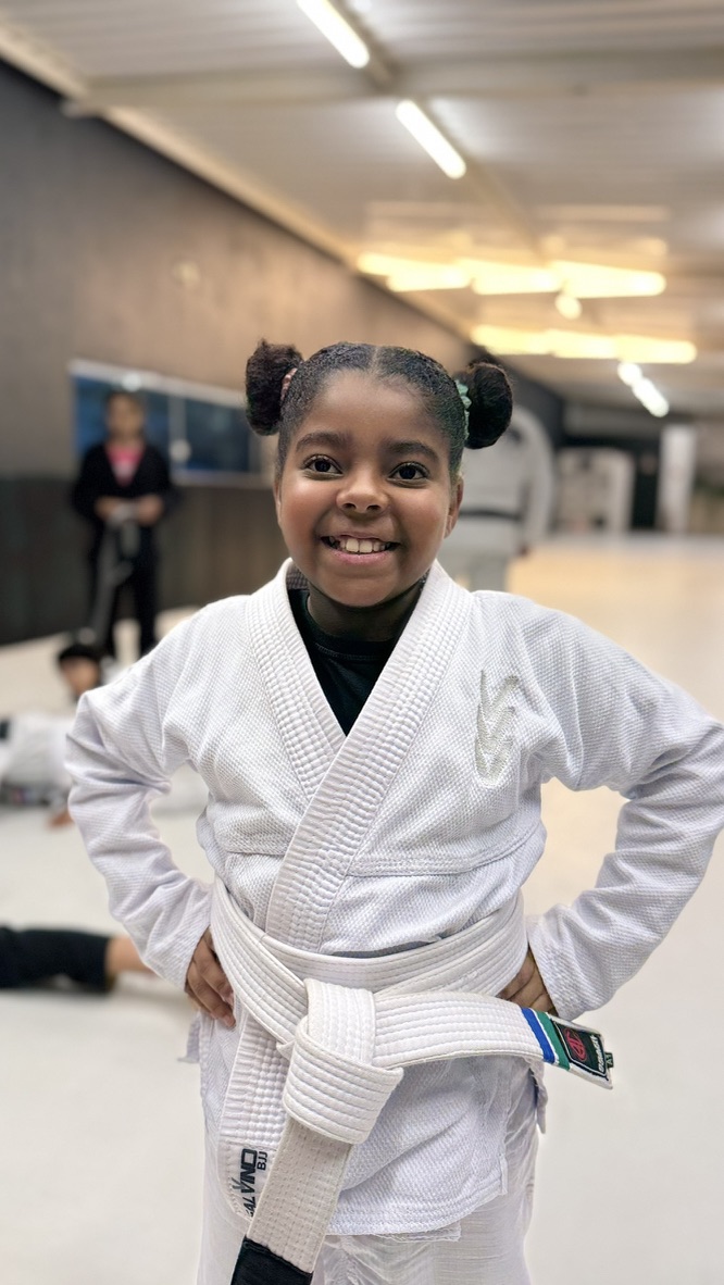 Aluna da Salvino BJJ sorrindo, de kimono e faixa branca